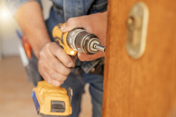Locksmith, maintenance and handyman with drill, home renovation and fixing, change door locks with power tools. Construction, building industry and trade with manual labour, diy and house repair