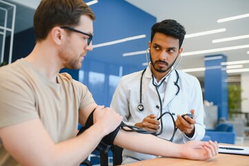 Fototapeta premium Indian Doctor Holding Dial While Measuring Man's Blood Pressure