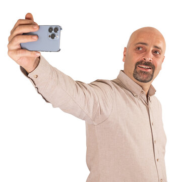 Taking selfie, portrait of Caucasian millennial male taking selfie. Standing man, transparent png image. Holding modern smartphone with three cameras. Smiling handsome bald and bearded man. Copy space