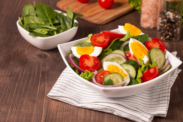 Appetizer healthy salad of fresh tomatoes, cucumber, spinach, lettuce and red onion. Vegan salad. Diet menu.