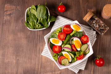 Fototapeta premium Appetizer healthy salad of fresh tomatoes, cucumber, spinach, lettuce and red onion. Vegan salad. Diet menu.