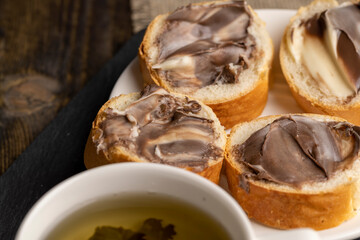 Green tea brewed in a mug and a baguette with chocolate butter