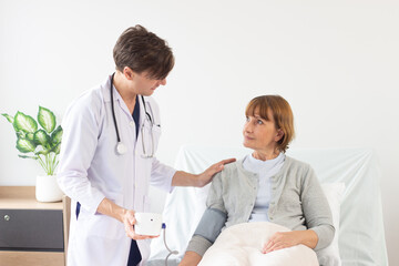 the doctor is examining the patient in the hospital. .Caucasian male doctor measuring blood pressure of female patient in hospital..