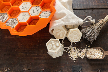 Orange silicone mold, with handmade, goat's milk, lavender, honey, and oat organic soap on a wooden...