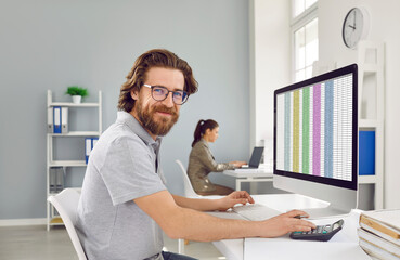 Portrait of happy male office worker. Business accountant at work. Handsome bearded man in gray T...