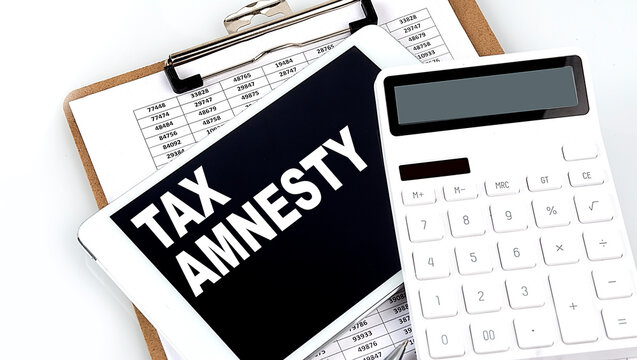 TAX AMNESTY text on a tablet with chart, calculator and pen