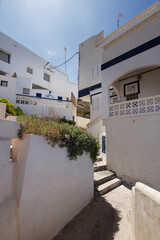 Narrow street with concrete stairs of a typical seaside village on the coast of Tenerife, white houses, seaside village in the background. La Caleta, Tenerife, Canary Islands Spain.