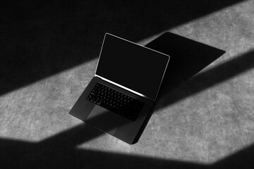 Laptop mockup template on a concrete background with deep shadows, real photo. Blank isolated to...