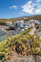 Fototapeta premium Views of the bay a beach with fishing village, with white houses. Tuneras in the foreground. Boats on the shore of the beach. Turquoise blue ocean. Yellow and brown hills in the background. In the bac