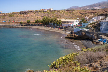Fototapeta na wymiar Views of the bay a beach with fishing village, with white houses. Tuneras in the foreground. Boats on the shore of the beach. Turquoise blue ocean. Yellow and brown hills in the background. In the bac