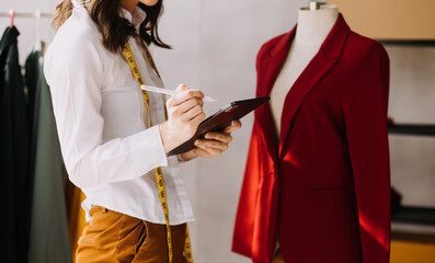 Fototapeta premium Fashion blogger concept, Young women selling clothes on video streaming.Startup small business SME, using smartphone or tablet taking receive and checking in studio