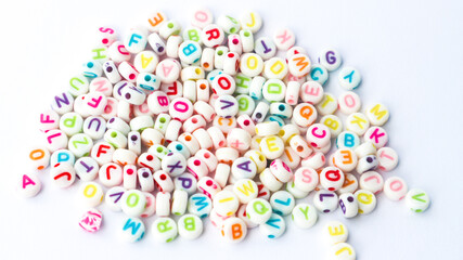 Collection of colourful beads blocks to make handmade jewellery bracelet names. heap of multi colored beads in street shop. Alphabets in kinder garden school for kids.