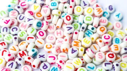 Fototapeta na wymiar Collection of colourful beads blocks to make handmade jewellery bracelet names. heap of multi colored beads in street shop. Alphabets in kinder garden school for kids.