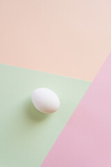 One white egg on multi color background, top view shot