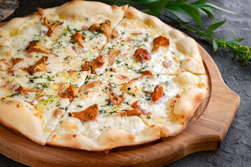 Pizza with chanterelles, cheese and rosemary. Italian pizza with mushrooms and herbs on a wooden board.
