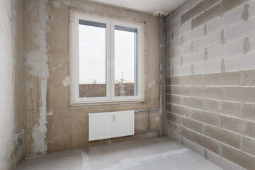 An empty room without decoration, with foam block walls and a window view of a high-voltage tower.