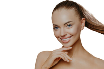 Tranquil undressed woman with healthy perfect skin, dark hair combed in pony tail, enjoys facial...