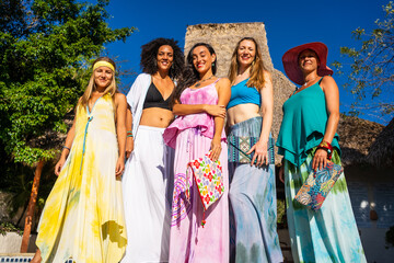 Fototapeta na wymiar Group of models standing with colorful long dresses outdoors