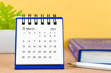 The March 2023 Monthly desk calendar for 2023 with a book on yellow background.