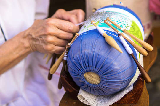 Bobbin lace equipment for handmade craft, lace-making tools. Lace textile made by braiding and twisting lengths of thread, which are wound on bobbins. It's held in place with pin set in a lace pillow.
