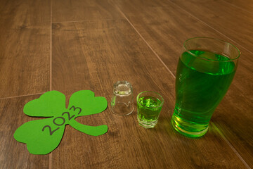 shot and pint glasses on wooden bar background filled with green spirit beer and shamrock, drunk at...
