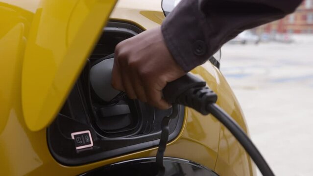 Slow Motion Electric car plugged into charge with cable in carpark