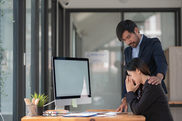 Businessman soothing frustrated businesswoman with her failed business while sitting in an office.