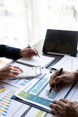 Businessmen meeting using laptop computers calculator stock market chart paper for analysis Quality improvement plan in business idea discussion meeting vertical image