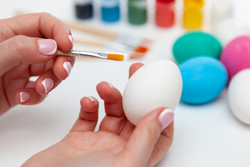 Painted Easter egg in the hands of a woman. A woman paints an Easter egg with watercolors. Close-up