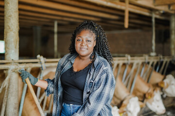 Young african farmer woman looking on camera while working inside cow shed