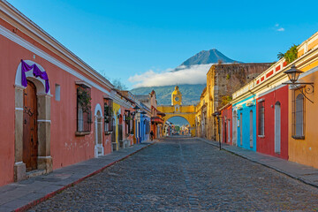 Antigua city main street at sunrise with the yellow arch and the Agua volcano in the background,...