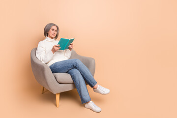 Fototapeta na wymiar Full length photo of shiny confident woman wear knitted pullover enjoying good book empty space isolated beige color background