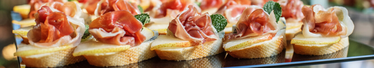 catering buffet table with snacks and appetizers. Set of canapés with jamon, bruschetta and cheese
