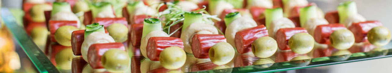 Set of appetizers with cucumber, sausage, olives and mushrooms. large glass food stand. Banner