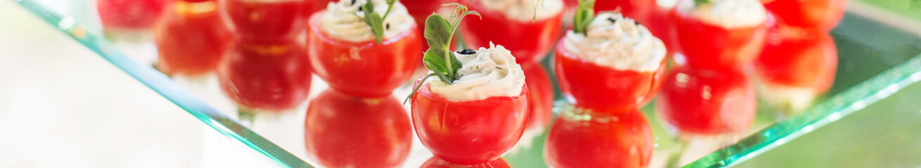 catering buffet table with snacks and appetizers. Stuffed cherry tomatoes with cheese. Banner