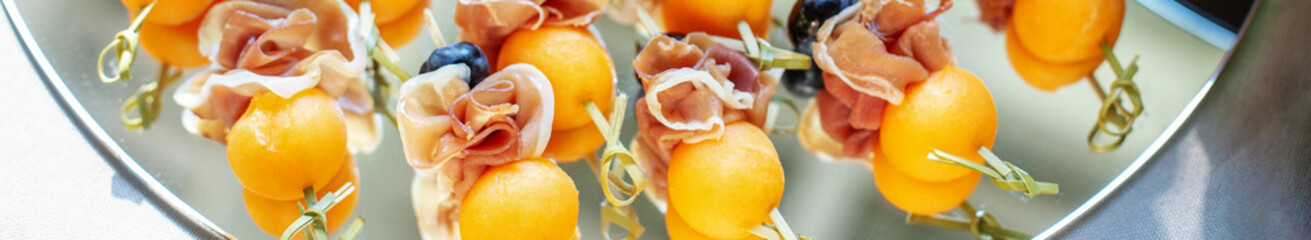 Delicious appetizers with prosciutto and peach at party. Close up. Catering event. Banner for site