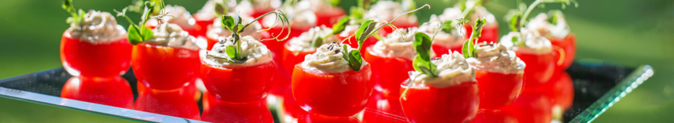 catering buffet table with snacks and appetizers. Stuffed cherry tomatoes with cheese. Banner