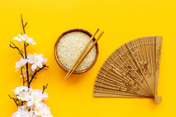 Asian table setting - rice bowl with cherry branch and fan. Top view