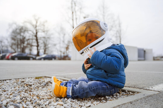 Little boy wearing astronaut costume playing outdoor. Child in astronaut helmet protected from the outside world. Concept of sustainability, environmental protection, future.