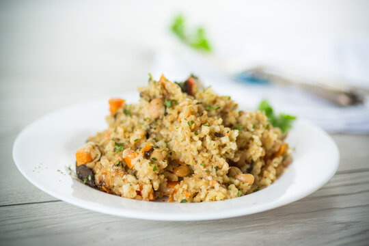 cooked bulgur with vegetables, carrots and dried mushrooms in a plate .