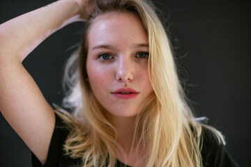 Fototapeta premium Beautiful young caucasian girl on dark background. Young blond hair female fashion model on black background. Fashion photoshoot.
