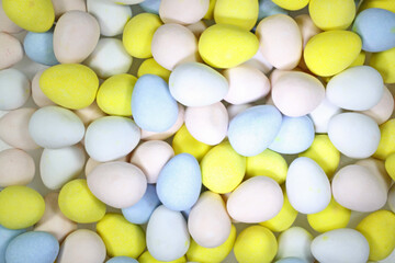 Background of pastel colored candy coated, chocolate Easter theme candies. Overhead photo of sweets.