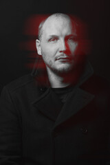 Obraz premium Lifestyle concept. Man with black coat studio portrait. Model with beard looking at camera with serious look. Red color split effect style. 3D glitch virtual reality effect