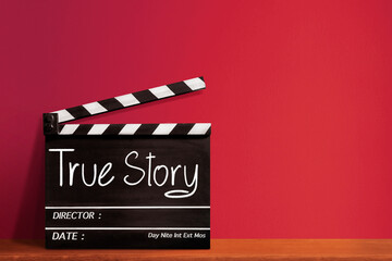 True story, handwritten text title on film slate for film industry, red wall background.