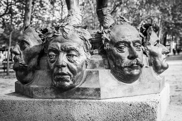 Close up on masks of The Mask Seller statue by Zacharie Astruc in the Luxembourg garden in Paris, France in black and white