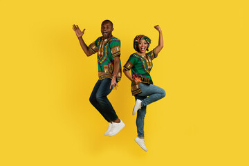 Fototapeta na wymiar Emotional black couple celebrating success on yellow, gesturing