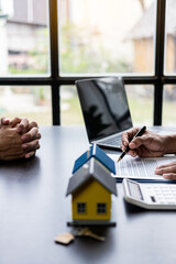 Real estate agents offer contracts and interest rates to buy or rent a residence. and businessman in front of house model, small building concept property and real estate insurance vertical image