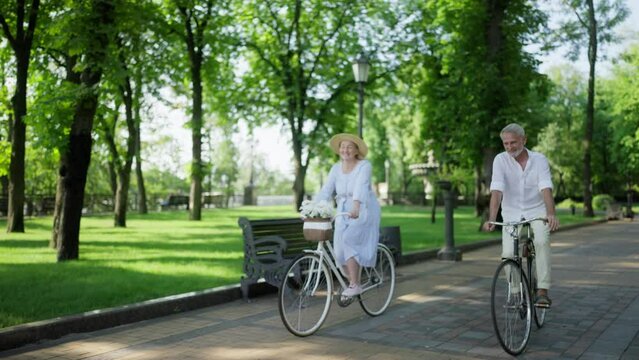 Mature couple enjoying riding bikes together in park, healthy lifestyle, dating