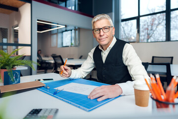 Mature man working on architectural project in office