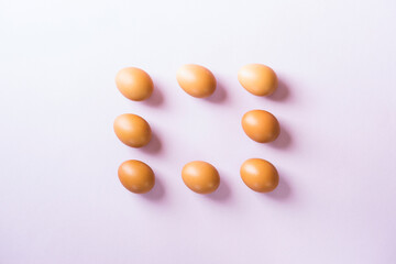 Eight  brown eggs flat lay on purple background with copy space on center